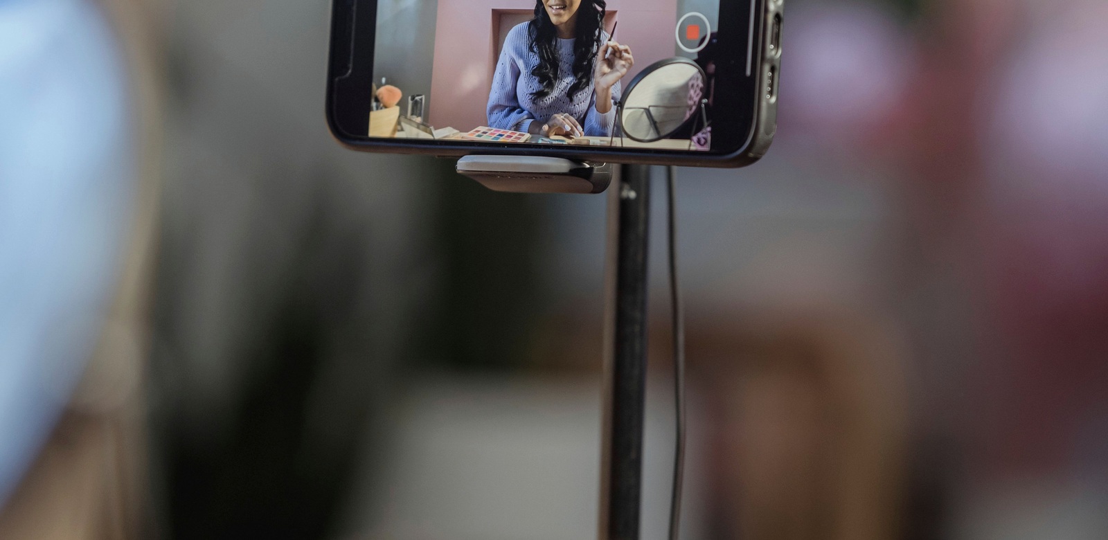A creator filming a beauty tutorial on a smartphone